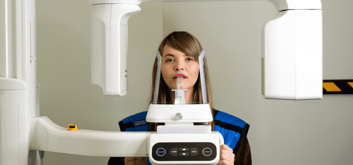 Donna durante esame radiografico dentale con macchina.