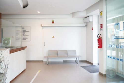 Sala d'attesa clinica con sedie e estintore