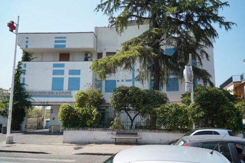 Clinica circondata da alberi e auto parcheggiate